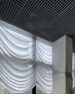 A modern industrial space with a concrete wall, metal beam, and curtains, featuring a sleek and contemporary atmosphere