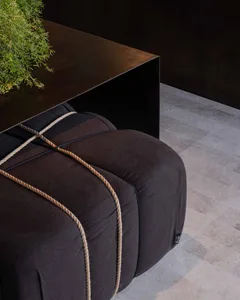 A well-lit living area with a black couch and rope detail on a hardwood floor