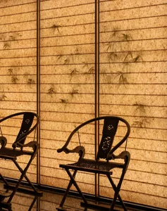 Two chairs placed in front of a wall with Asian paper artwork, creating an inviting atmosphere