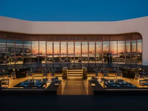 Elegant dining space with multiple tables, chairs, and wine glasses, creating a comfortable environment for social gatherings