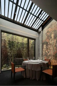 Elegant dining space with a large table, chairs, wine glasses, and natural light from a window