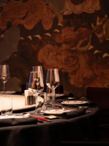 Elegant dining area with a round table set for a formal dinner, featuring white plates, glasses, and wine glasses, in a sophisticated setting