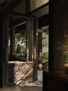 A welcoming entrance with lush greenery and potted plants surrounding the doorway, creating a cozy atmosphere