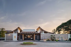 Warm and inviting Asian-style building with a large wooden structure, archway entrance, and courtyard with potted plants