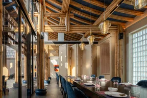 Cozy restaurant interior with wooden walls and ceiling, featuring tables, chairs, decorative vases, and well-planned lighting