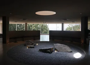A serene indoor space with a large stone circle and benches, encouraging interaction and calmness