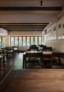 An empty restaurant with wooden tables and chairs, creating a warm and inviting atmosphere with ample seating options
