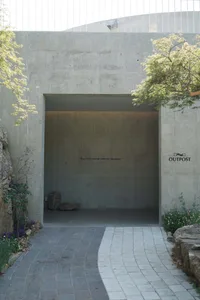 A modern indoor space with a concrete wall, a doorway, and two potted green plants
