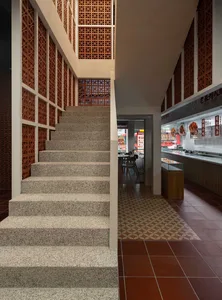 A well-lit restaurant interior with a stone staircase, chairs, and dining tables, creating a welcoming atmosphere for patrons