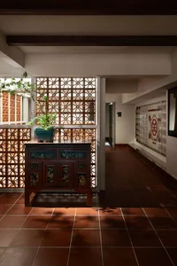 A hallway with a tile floor, two potted plants on either side, and a central vase, adding greenery and decoration