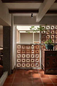 A well-lit interior space with a wooden door and a window featuring a decorative lattice pattern, creating a warm and inviting atmosphere