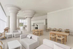 Open living area with a white couch, chairs, dining tables, and natural light from multiple windows