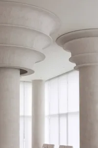 Empty lobby with two central pillars, concrete walls, and a minimalist atmosphere
