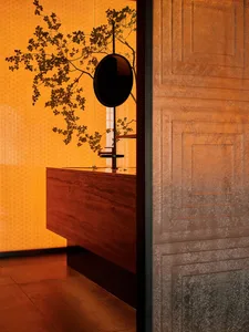 A warm and inviting bathroom with an orange color scheme, featuring a sink area with a mirror, two potted plants, and a cozy atmosphere