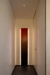 A well-lit hallway with a white wall, two doors, and a red light strip, creating a bright atmosphere