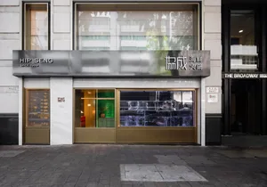 Spacious Asian restaurant with a glass front door, dining tables, chairs, and potted plants, creating a comfortable and inviting atmosphere