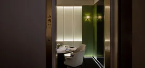 A modern restaurant interior with a dining table surrounded by chairs, vases, and multiple place settings, creating an inviting and sophisticated ambiance