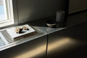 A modern kitchen with a metal countertop featuring two bowls and three rocks, with a clean and organized atmosphere