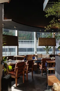 Modern restaurant interior with dining tables, chairs, potted plants, and warm lighting