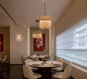 A modern dining area with a round table, chairs, and decorative items, surrounded by artwork on the walls, creating a sophisticated atmosphere for socializing and dining