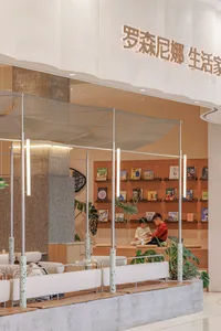A calm and inviting bookstore with wooden shelves, multiple chairs, and people browsing through books