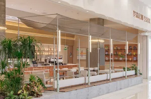 A restaurant interior with multiple chairs and tables, potted plants, and an inviting atmosphere