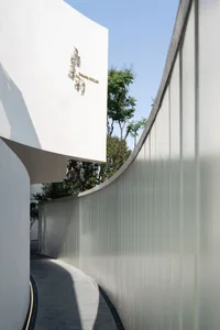 A modern building with a large glass wall and surrounding trees, creating a calm and serene atmosphere