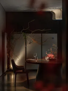 Intimate dining space with a darkly lit room, a dining table, and two chairs, with a wine glass on the table