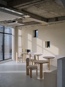 Open modern living space with natural light, two couches, chairs, a dining table, and a potted plant