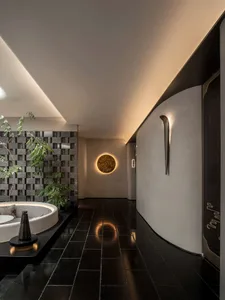 Cozy modern living area with a circular table, chairs, potted plants, and black tile flooring