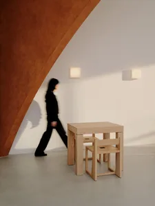 A woman walks past a wooden dining table in a casual restaurant setting with two chairs and wooden walls creating a warm atmosphere
