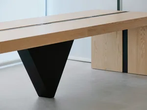 A modern dining space with a large wooden table on a concrete floor, giving an industrial feel