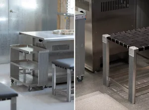 Modern kitchen dining space with stainless steel and black countertops, metal tables, and dining chairs