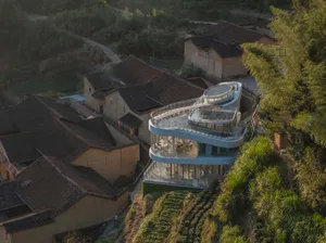 A modern house on a hillside with a large glass structure, blending traditional and contemporary architectural elements