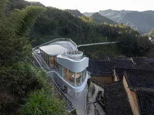 Modern building with a curved roof, glass wall, and hillside location overlooking a valley