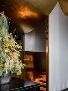Warm and inviting interior staircase with wooden steps, metal railing, and a decorative vase at the bottom