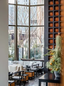 Spacious lobby with high ceilings, large windows, modern design, and natural light, featuring chairs and potted plants