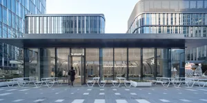 Modern building with a large glass wall, various windows, and outdoor seating areas