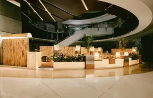 A welcoming indoor space with a circular staircase surrounded by plants, decorative elements, and two benches, creating a lush atmosphere