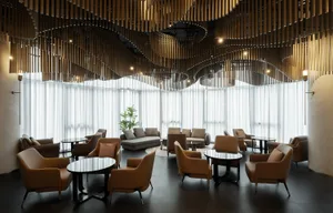 A well-lit interior design featuring multiple seating areas, dining tables, and natural light from windows, creating an inviting atmosphere for social gatherings or relaxation