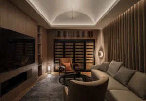 A well-lit living room with a modern design, featuring a couch, chairs, and wine glasses on surfaces