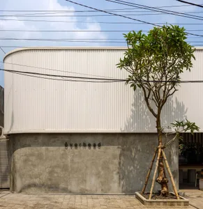 A serene photo of a modern building with a white exterior, surrounded by two trees and a calm atmosphere