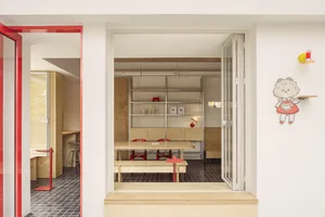 Modern dining room with wooden floors, white walls, and red accents, featuring a dining table and chairs, and two windows