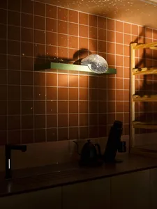 Cozy kitchen with a sink, mirror, and various items on the countertop, including cups, a kettle, and a bottle, with a focus on practicality and organization