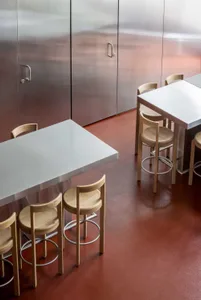 Industrial dining space with a metal table and wooden chairs, well-lit with natural light or overhead lighting