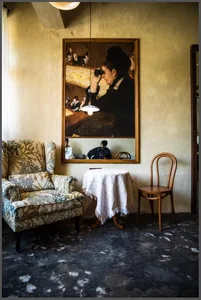 Cozy living space with a large painting above a table, two chairs, and a dining table, creating a warm and inviting atmosphere