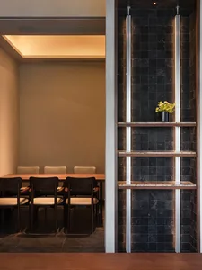 A well-lit dining area with a long table and multiple chairs, surrounded by modern architecture-inspired design