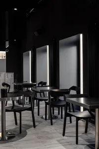 Sophisticated restaurant interior with black tables and chairs, multiple dining tables, and a modern atmosphere
