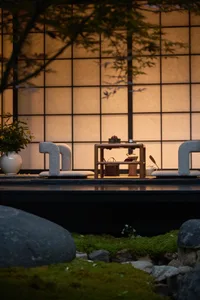 Cozy Asian-style living area with a wooden table, chairs, couches, and potted plants, featuring a serene and inviting traditional Japanese interior