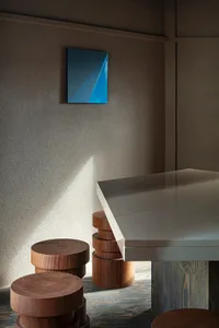 A dining table surrounded by four wooden stools, with two chairs on each side, creating a cozy seating arrangement in a modern yet warm space
